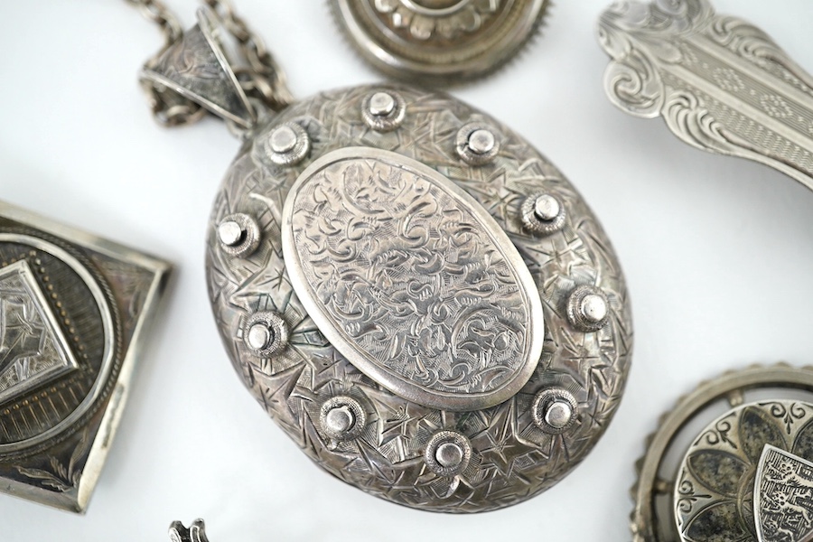 An oval engraved white metal enclosed locket and chain and five assorted white metal brooches. Condition - fair